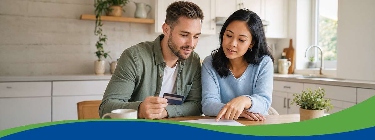 Couple sitting at table in kitchen looking at credit card statement